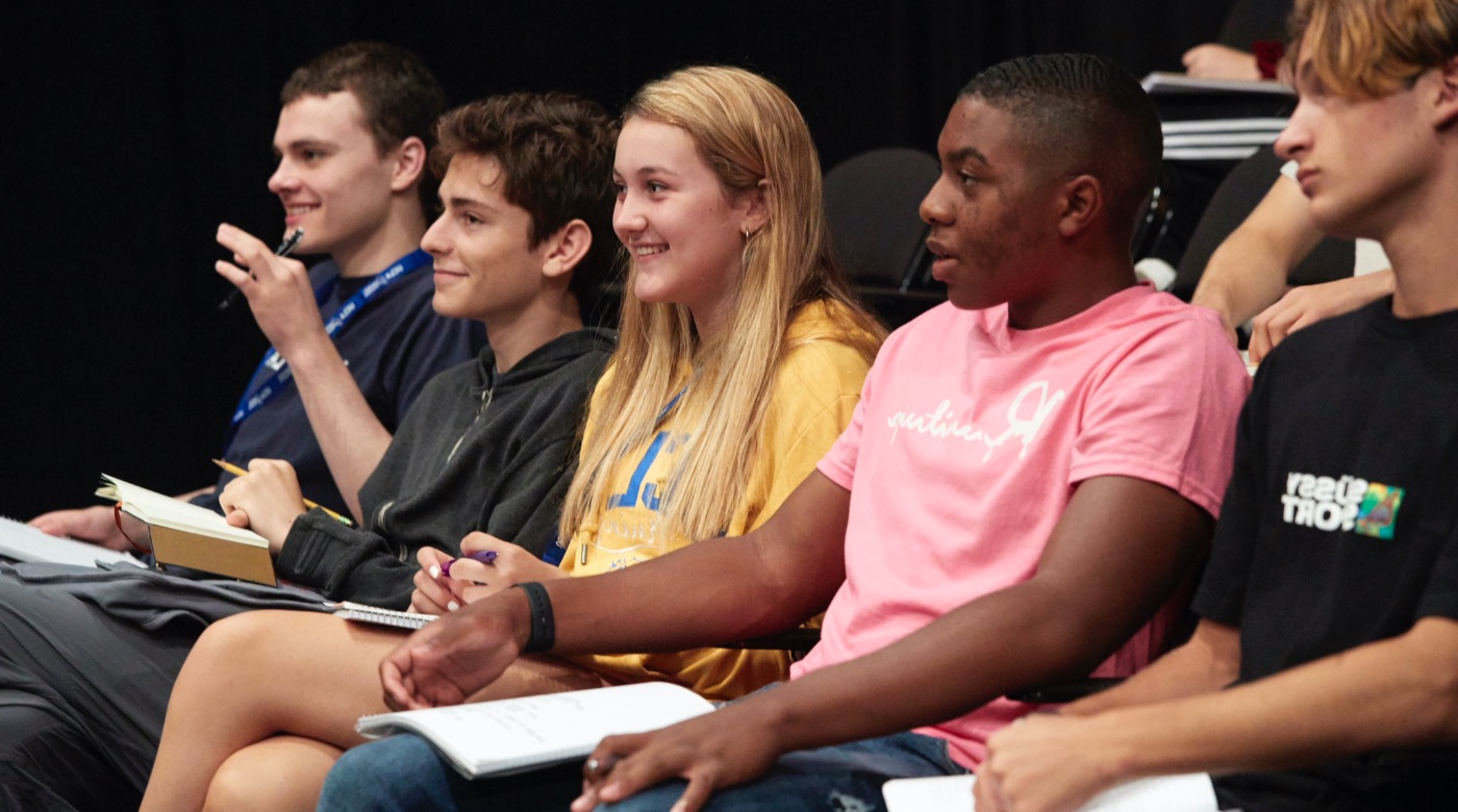 Group of students smiling as they listen to a lecture.