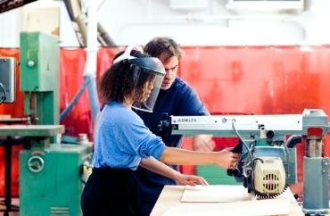 A student working on a piece of machinery as an instructor overlooks.