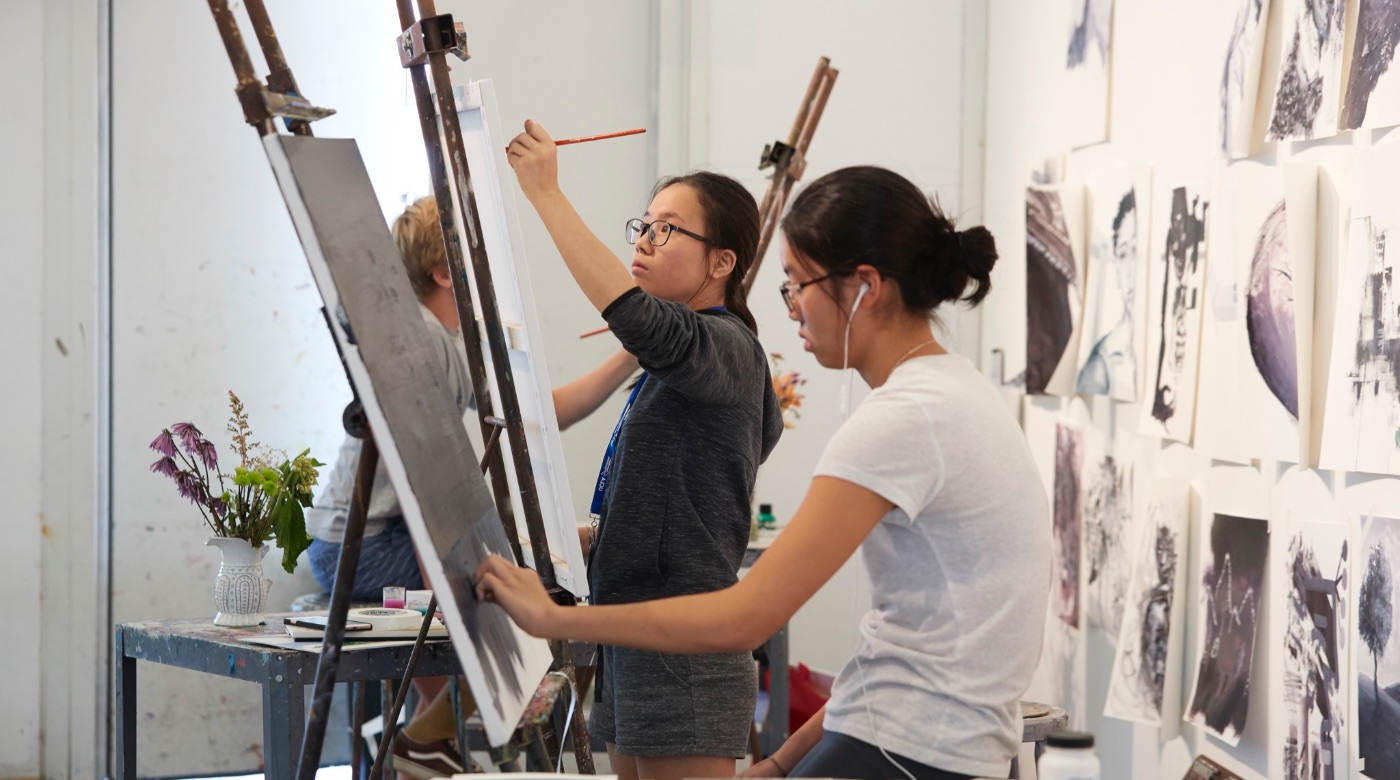 Three students painting on three easels.