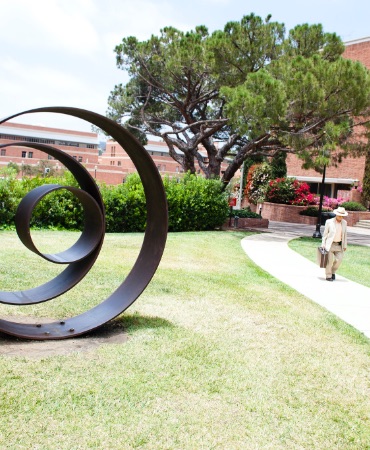 Circular sculpture on walking path. Sculpture consists of four circles nested within one another.