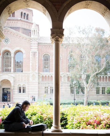 View of Powell Library and student studying under an archway.