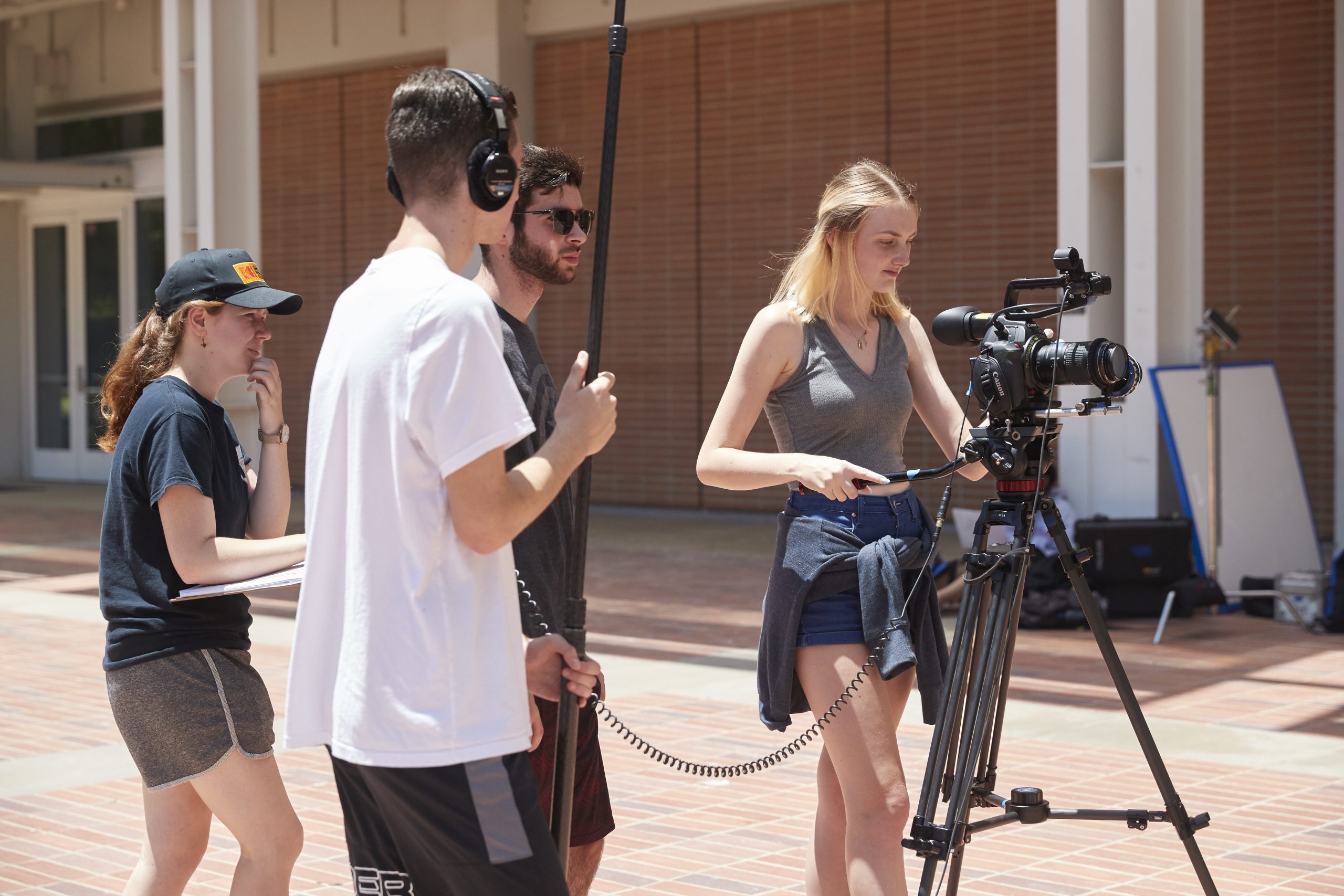 Two female students and two male students operate a camera on a tripod on the UCLA campus.