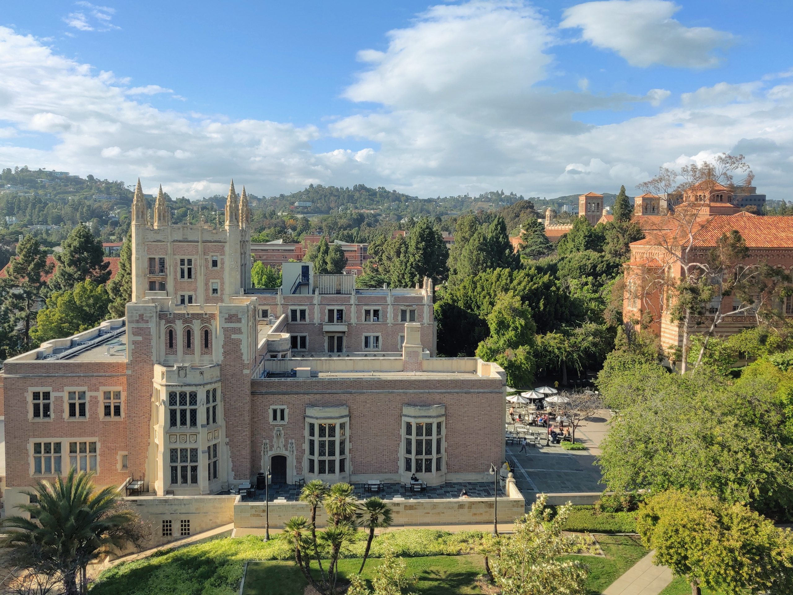 A scenic overhead view of the UCLA campus showing Kerckhoff Hall in the foreground and the hills of Los Angeles in the background.