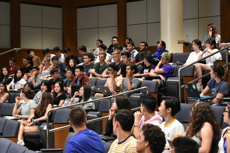 A view of students sitting in a large lecture hall.